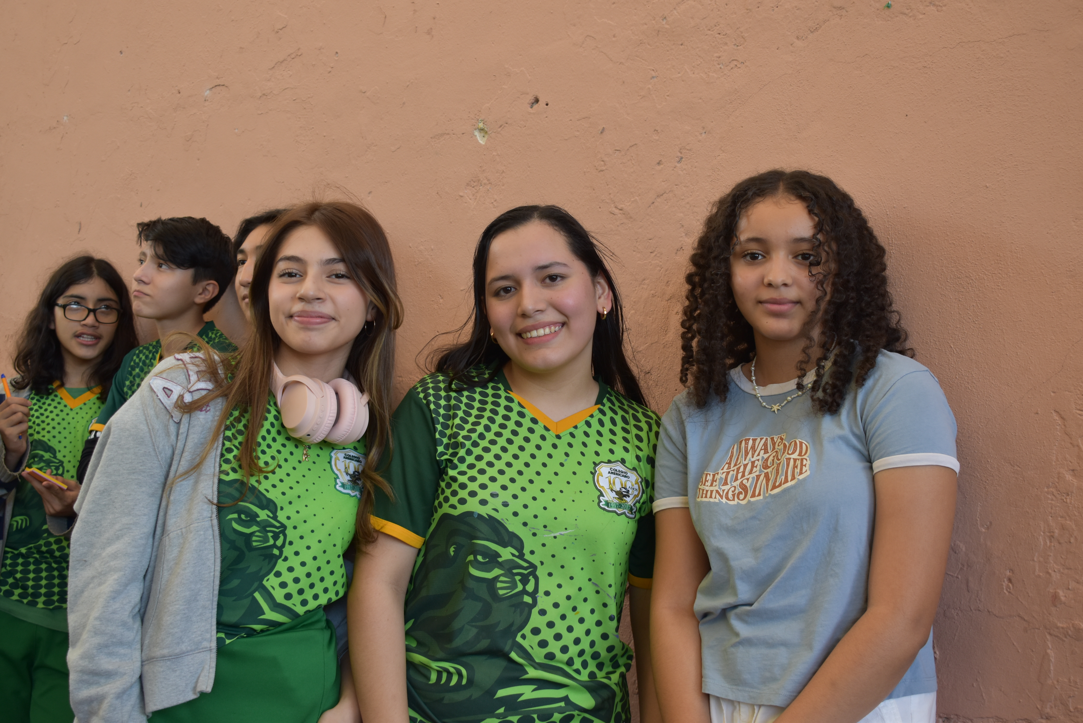 Alumnas del colegio americano posando para una foto con el uniforme deportivo, una de ellas con unos audifonos.